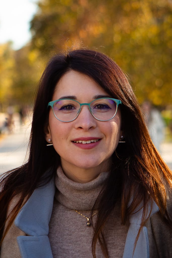 Ritratto di donna sorridente con occhiali nel parco.